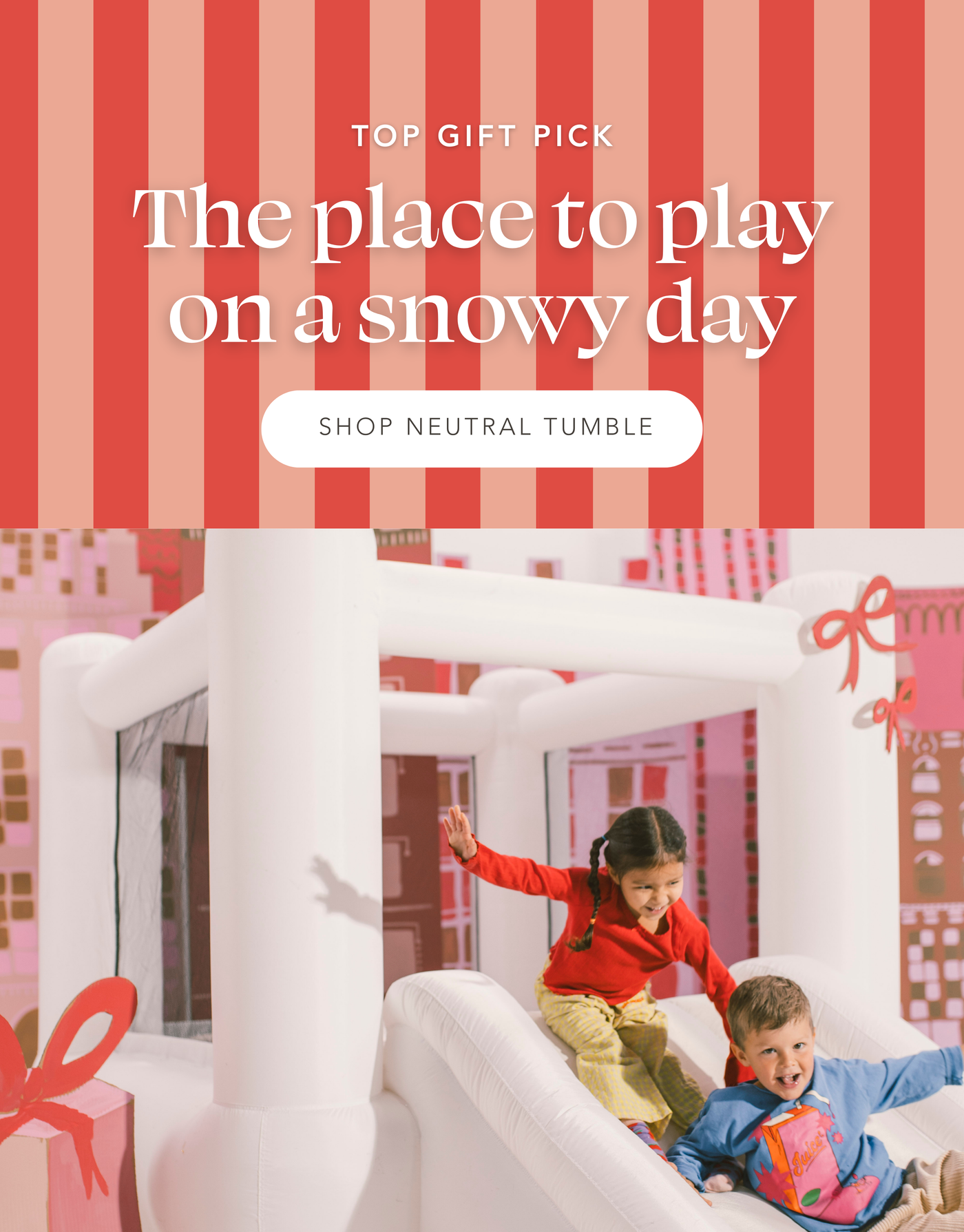 Kids sliding down slide on Tumble Bounce House in front of cardboard cityscape. Top Gift Pick: The place to play on a snowy day | Shop Neutral Tumble