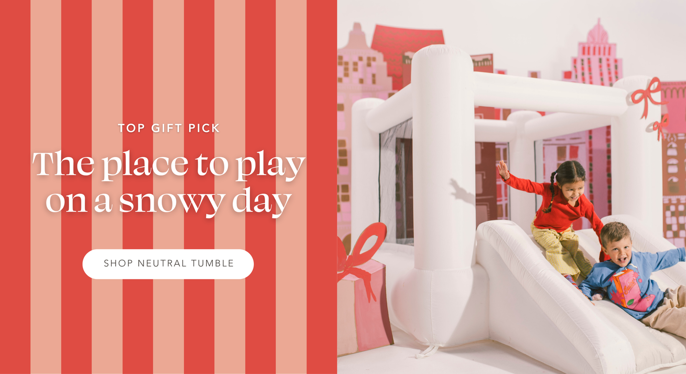 Kids sliding down slide on Tumble Bounce House in front of cardboard cityscape. Top Gift Pick: The place to play on a snowy day | Shop Neutral Tumble