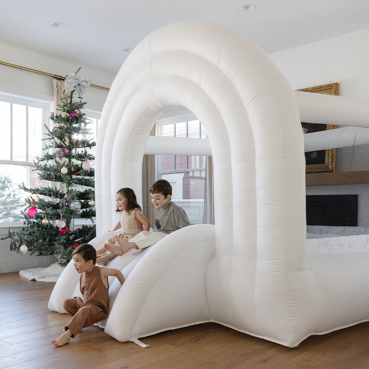 Kids sliding down neutral rainbow slide next to Christmas tree