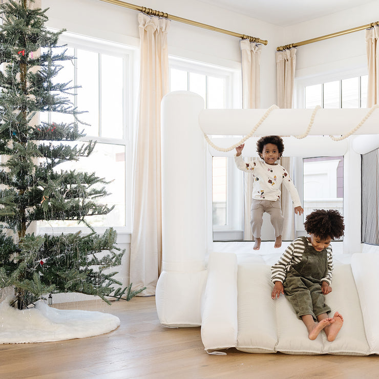 kids jumping in neutral bounce house next to Christmas tree