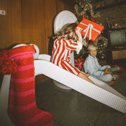 Kid sliding down indoor slide holding a present 