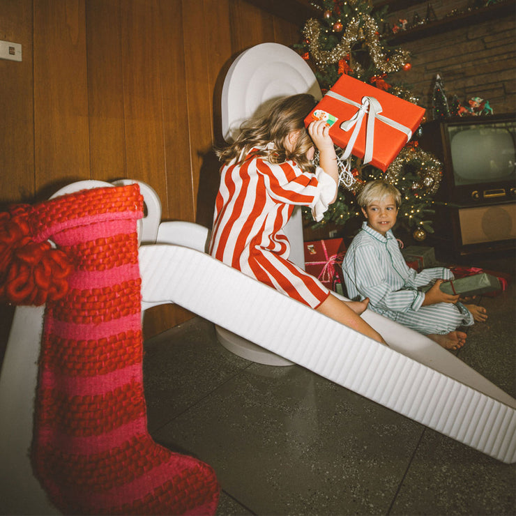 Kid sliding down indoor slide holding a present 